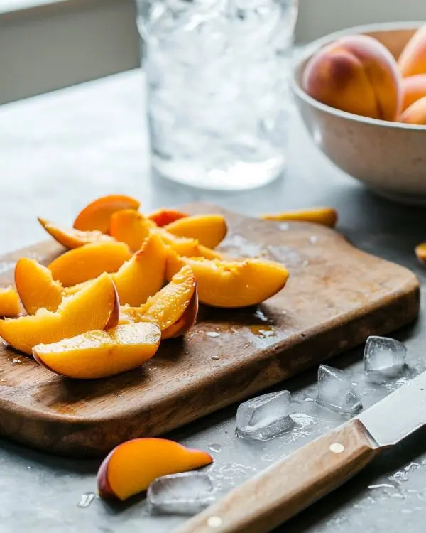Freezing Peaches 3 Freshly Freezing Peaches on cutting board with knife and peach skins, ice water bowl in background