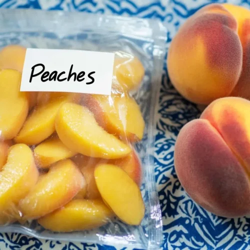 Freezing Peaches 5 Fresh Georgia peaches on kitchen counter next to freezer bags of sliced frozen peaches ready for storage