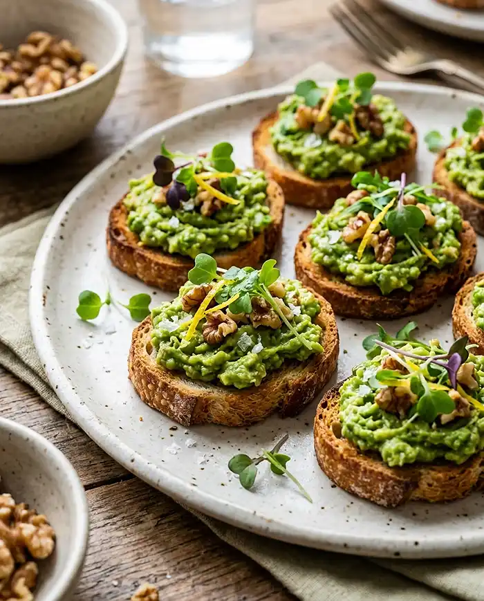Breakfast Toast Recipes 2 Mini avocado toasts topped with toasted walnuts and flaky sea salt
