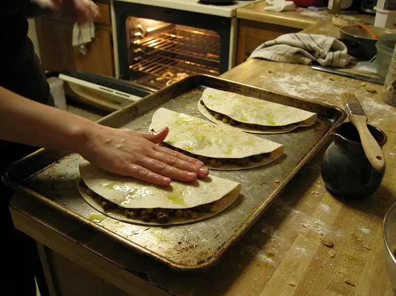 Crispy Sheet-Pan Oven Quesadillas 5 Four folded quesadillas flat on the oiled tray